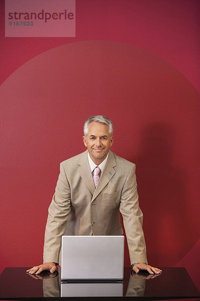 Businessman with laptop standing at conference table