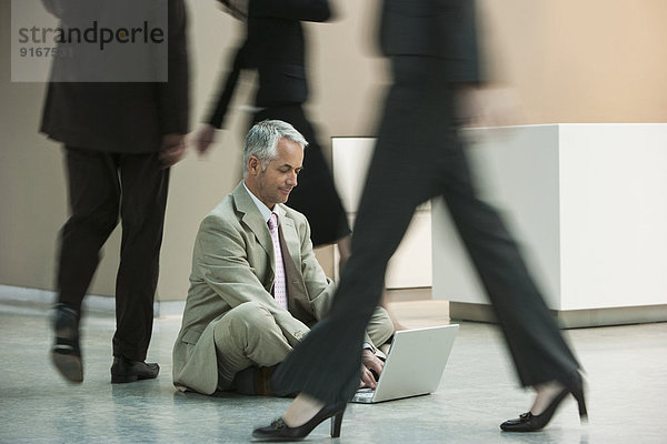 Businessman using laptop on busy office floor