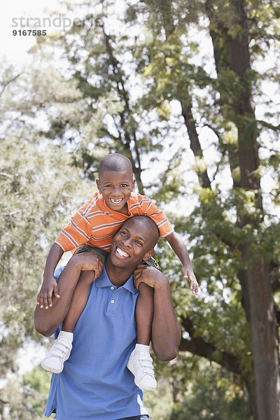 Father carrying son on shoulders in park