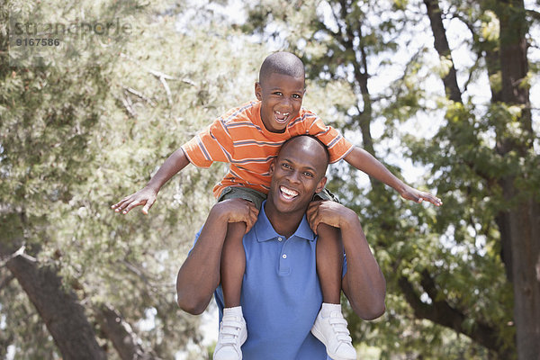 Father carrying son on shoulders in park