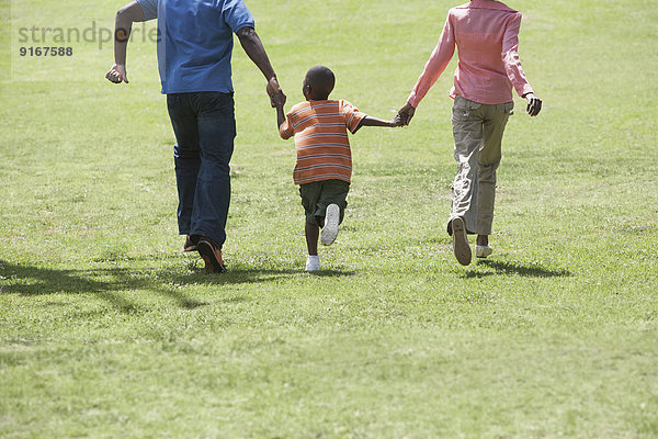 Boy holding parents' hands in park