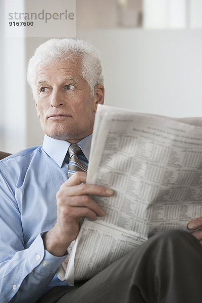 Caucasian businessman reading newspaper in office