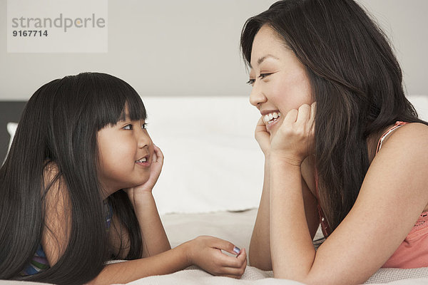 Mother and daughter talking on bed