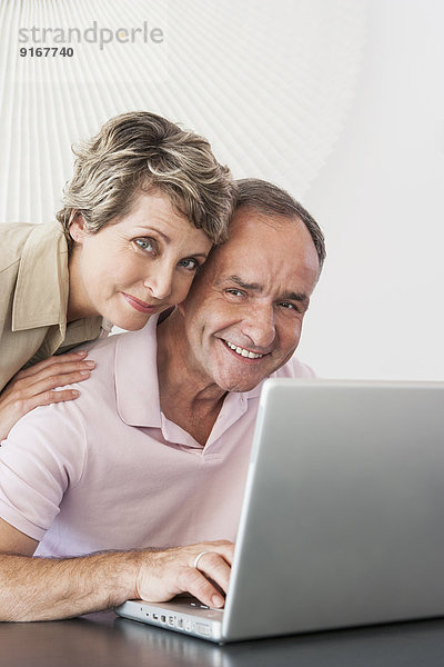 Woman hugging husband at laptop