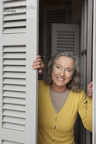 Woman peering out window shutters