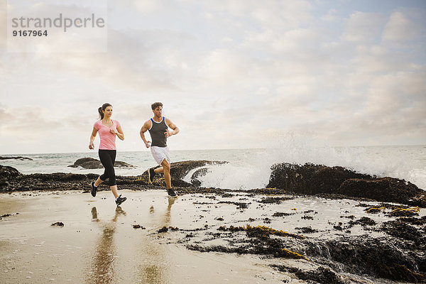 Caucasian couple running on beach