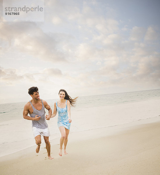Caucasian couple running on beach