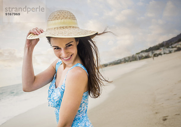 Caucasian woman wearing straw hat on beach
