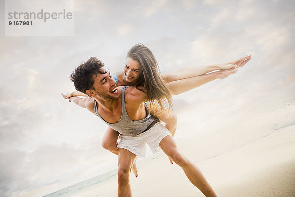 Caucasian couple playing on beach