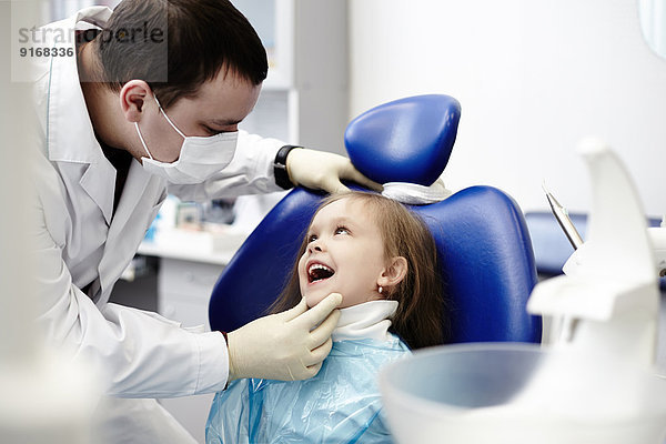 Caucasian dentist examining girl's teeth