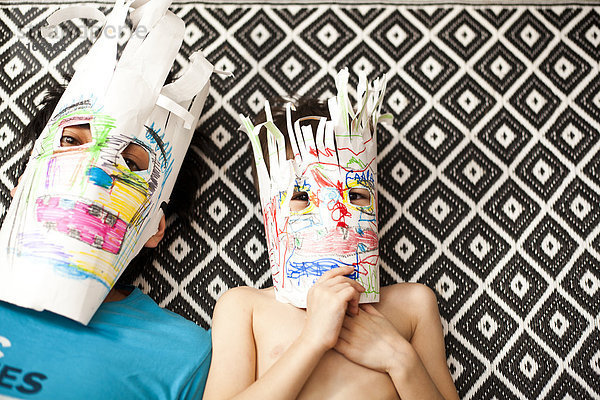 Father and son wearing colorful masks on carpet