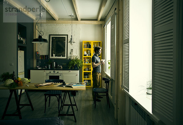 Caucasian man looking out kitchen window