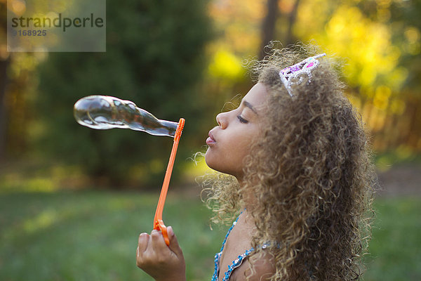 Mixed race girl blowing bubbles outdoors