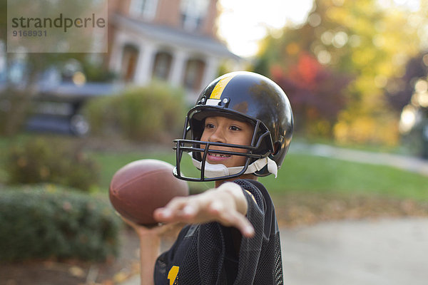 Mixed race boy playing football outdoors