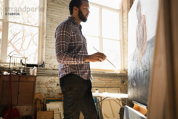 Mixed race artist painting in studio