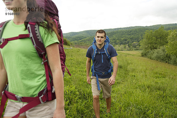 Caucasian couple hiking in rural field