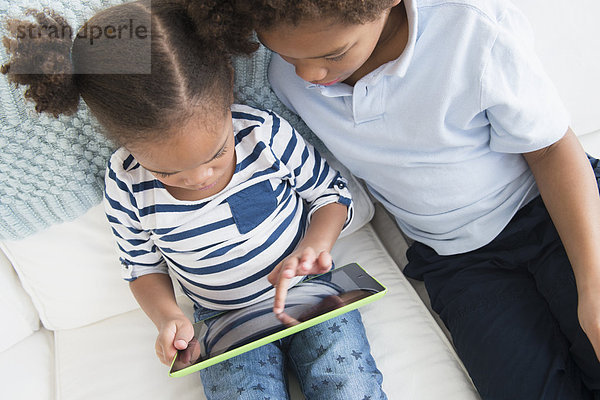 Black children using digital tablet together