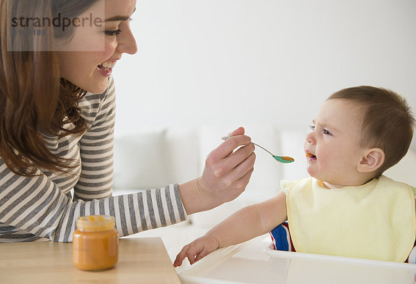 Mother feeding baby in high chair