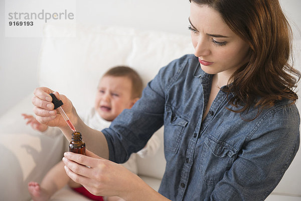 Mother giving crying baby medicine