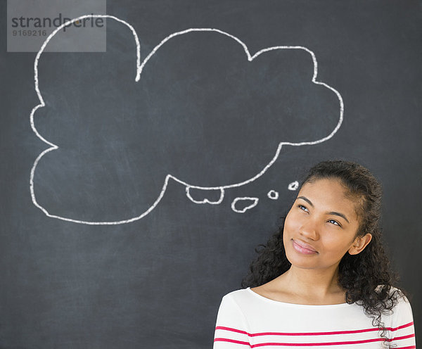 Mixed race woman under thought bubble on chalkboard