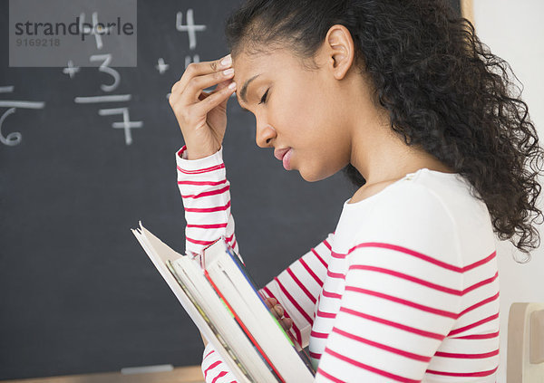 Frustrated mixed race teacher rubbing her forehead