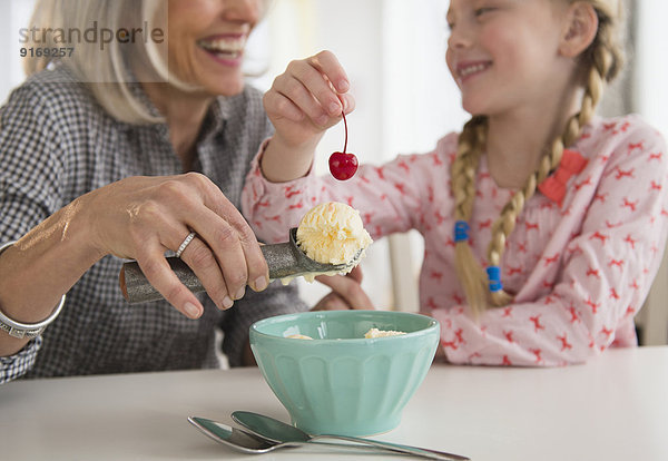 Senior Caucasian woman and granddaughter making ice cream sundae