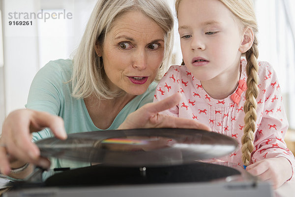 Senior Caucasian woman and granddaughter listening to records