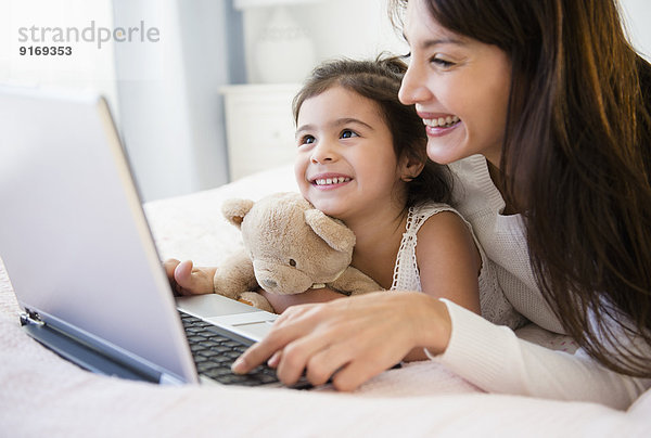 Hispanic mother and daughter using laptop together