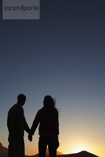 Silhouette of Caucasian couple holding hands