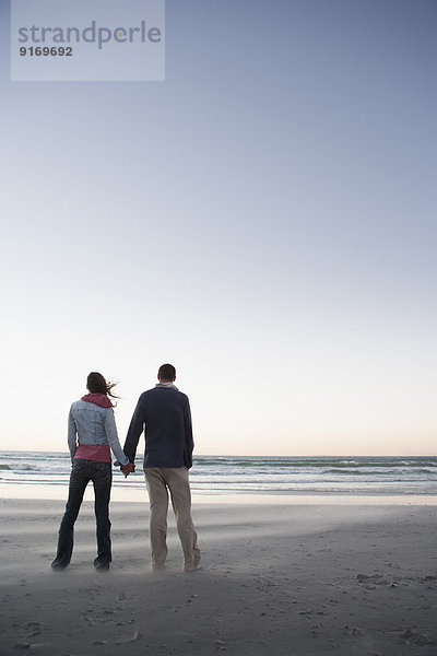 Caucasian couple holding hands on beach