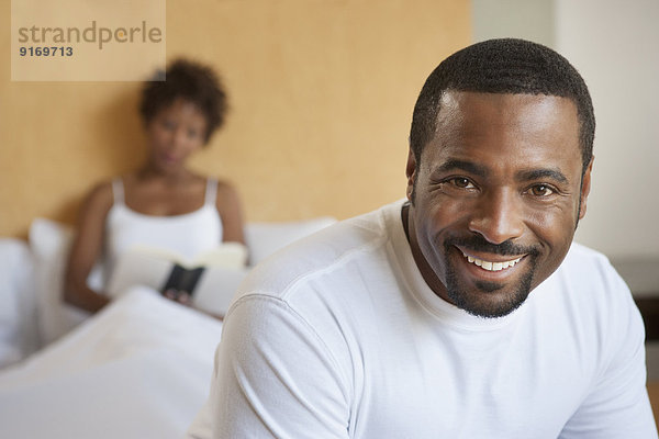 African American man sitting on bed