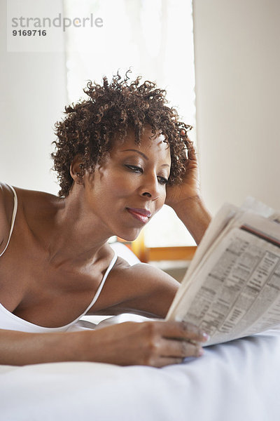 African American woman reading in bed