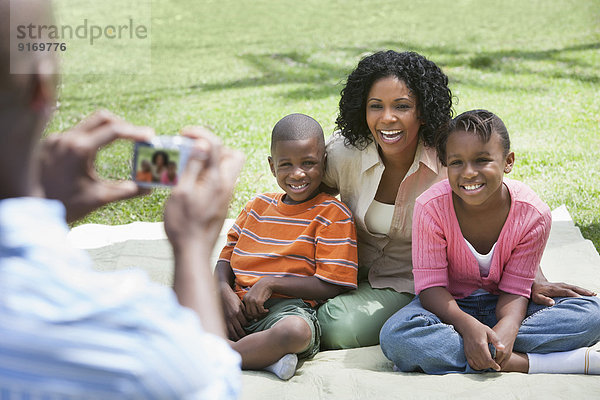 Family taking picture together on picnic blanket