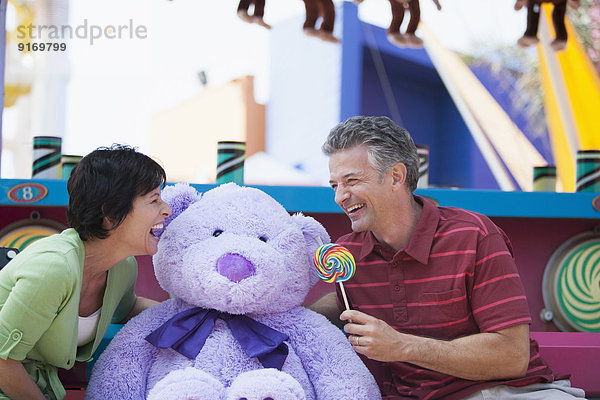 Caucasian couple with teddy bear at theme park