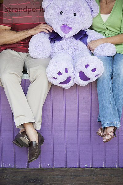 Caucasian couple with teddy bear at theme park