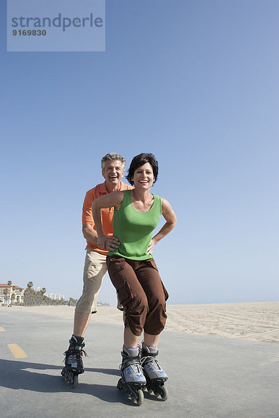 Caucasian couple rollerblading by beach