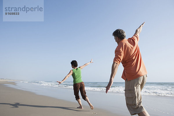 Caucasian couple playing on beach