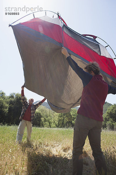 Senior Caucasian couple pitching tent in field