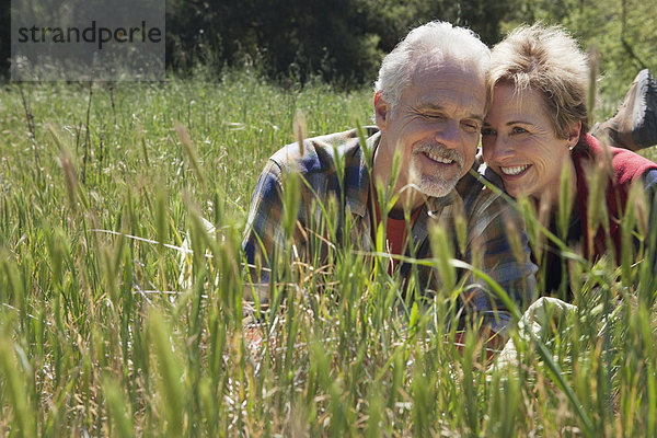 Senior Caucasian couple laying in tall grass