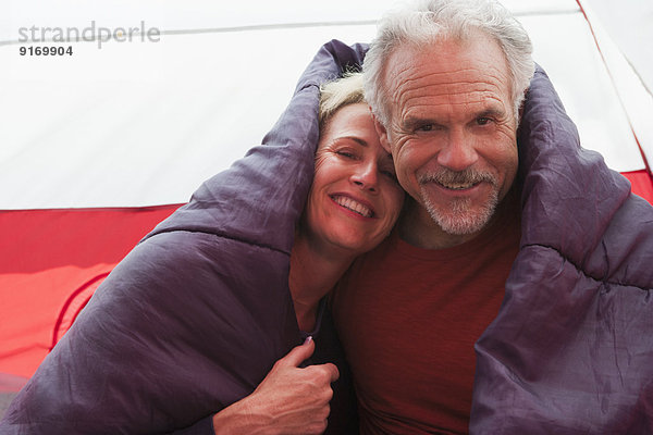 Senior Caucasian couple in sleeping bag in tent