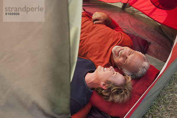 Senior Caucasian couple relaxing in tent