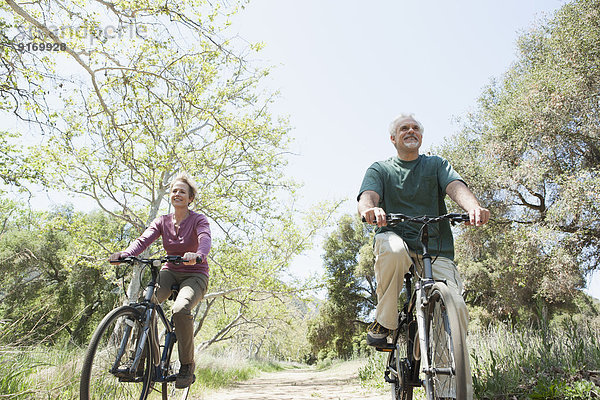 Senior Caucasian couple riding bicycles on rural path