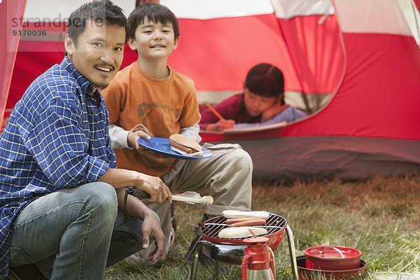 Father and son cooking at campsite