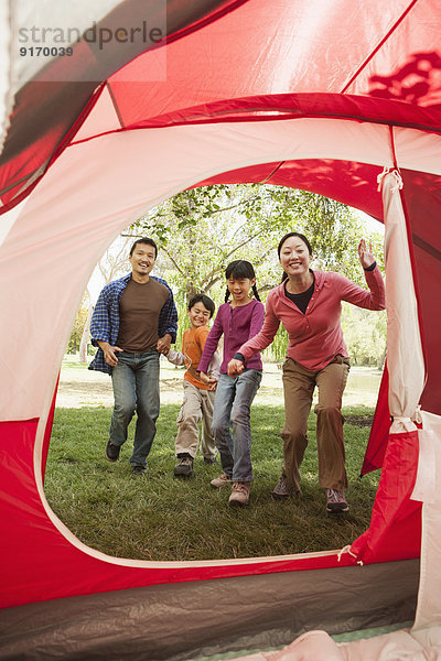 Family running to tent at campsite