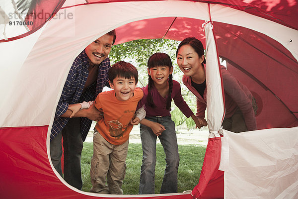 Family peering in tent at campsite