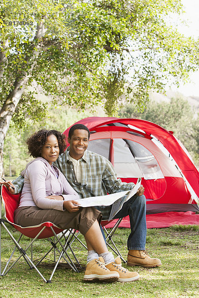 Couple reading newspaper together at campsite