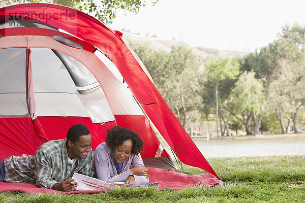 Couple reading newspaper together in tent