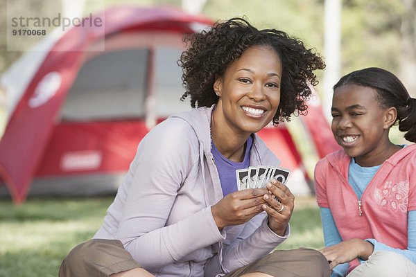 Mother and daughter playing cards at campsite