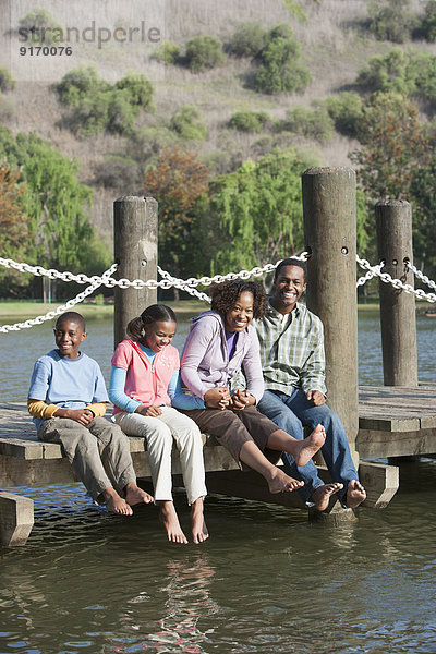 Family sitting on wooden dock in lake