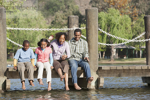 Family sitting on wooden dock in lake